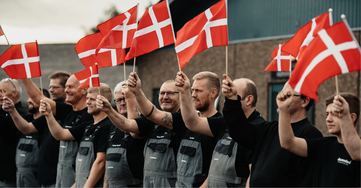 Gastrolux team holding Danish flags outside the factory in Ryomgaard